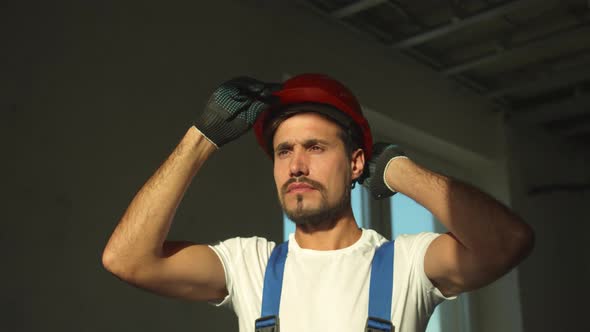 Builder Stands and Puts on Protective Helmet