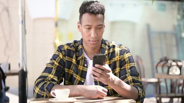 Young African Man Using Smartphone Outdoor Cafe