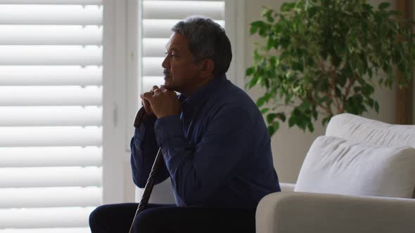 Senior mixed race man sitting and holding his head in thought