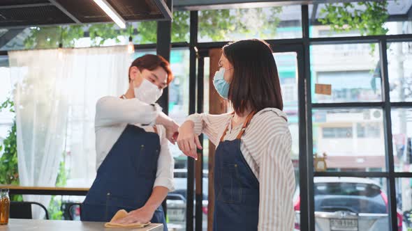 Asian cafe worker wear mask, walk in restaurant with confidence and greeting waiter by elbow bump.