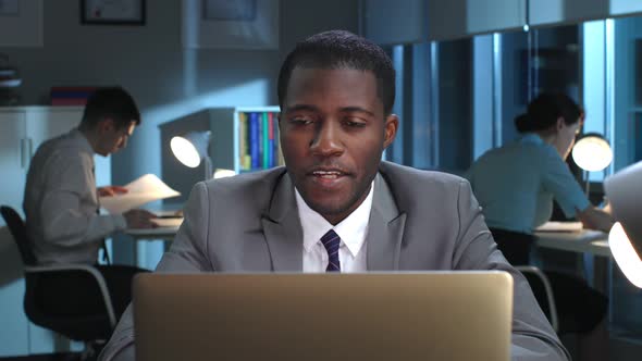 AfricanAmerican Businessman Have Video Conference on Laptop in Dark Office