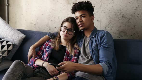 Cute Happy Couple of Young Hipsters Cuddling on the Couch Trying to Find a Perfect Tv Channel