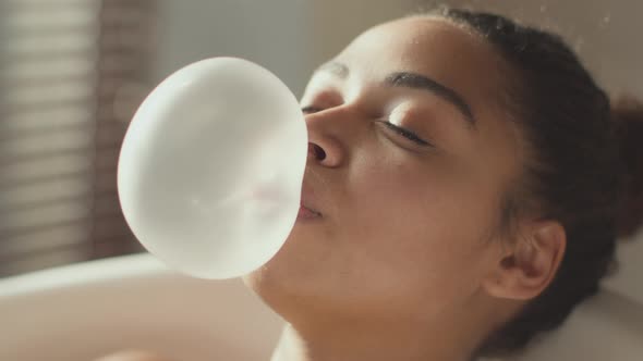 Young Carefree African American Woman Blowing Bubble Gum It Bursting on Her Face Lady Laughing