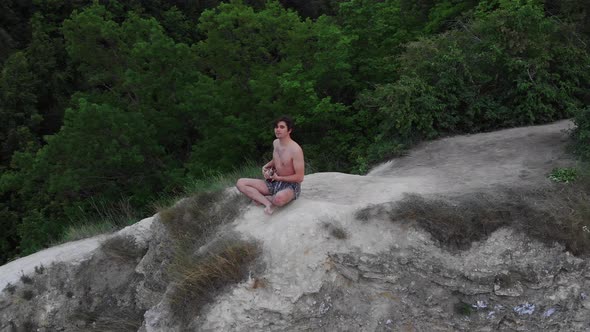 Young Shirtless Man Playing Ukulele on the Cliff