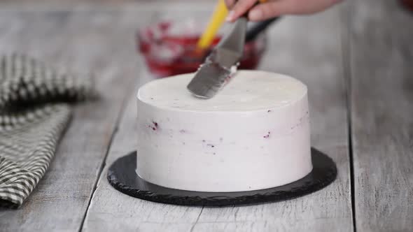 A confectioner prepares a cream cake, Dessert on a white table in the kitchen