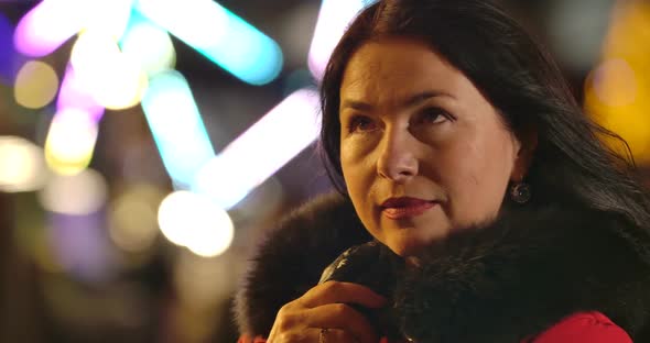 Portrait of Thoughtful Caucasian Woman Standing at the Background of Colorful Carousels Outdoors