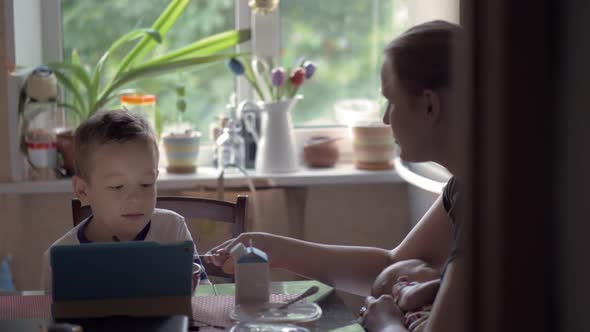 Mum Playing with Son and Nursing Baby During the Breakfast