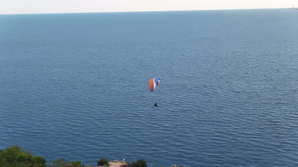 Aerial Following Paragliders Over Sea With View Of Mountains And Green