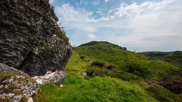 Panorama motion time lapse of rural landscape with large rocks in grass field on hillside during a c alt