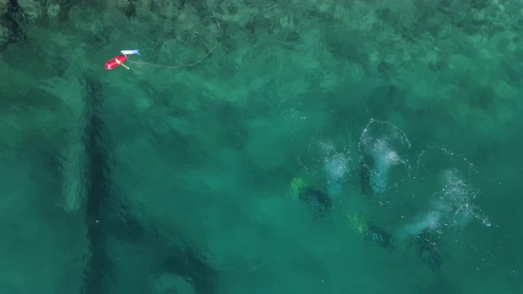 High view looking down at a group of scuba divers underwater with their bubbles breaking the surface