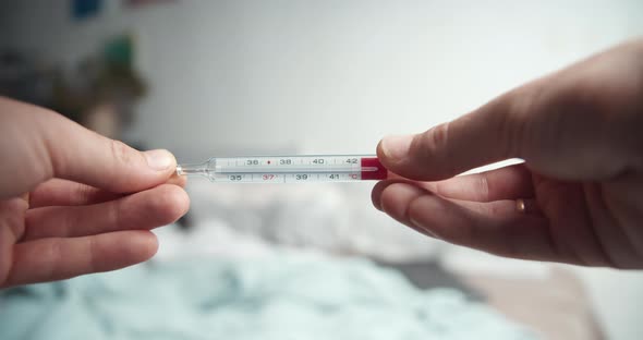 Male Hands Holding Analogue Thermometer with Very High Temperature