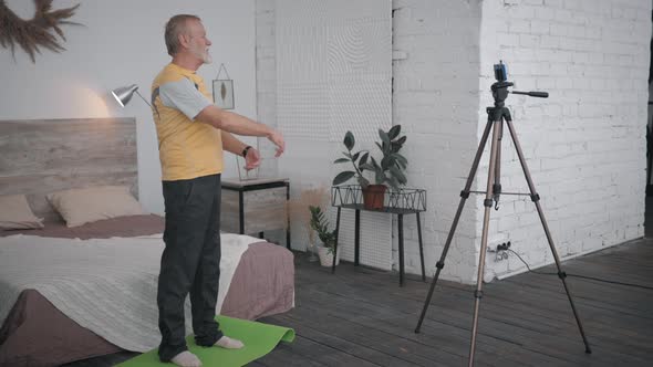 Influencers Blogger, Aged Man Shows an Exercise for Joints on Phone Camera Recording Sport Vlog