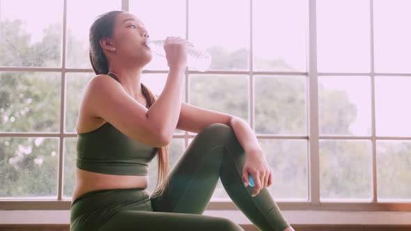 Asian girl drinking water after exercising at home.