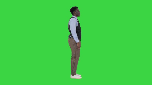 Young African American Businessman Standing Looking Straight Ahead and Nodding His Head on a Green