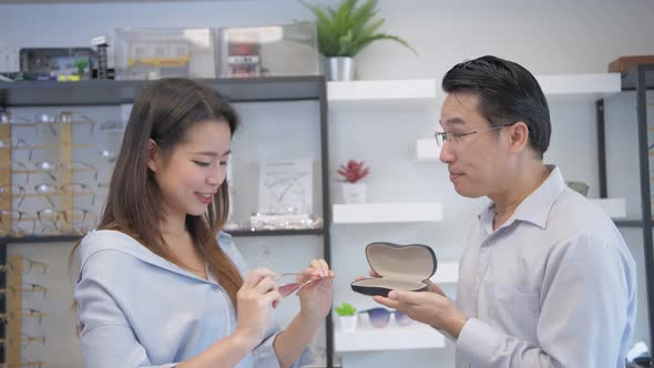 Optical shop concept. The shopkeeper is introducing glasses to customers. 4k Resolution.