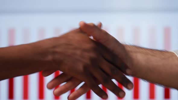 Handshake: two men shake hands on the background of multimedia in the office
