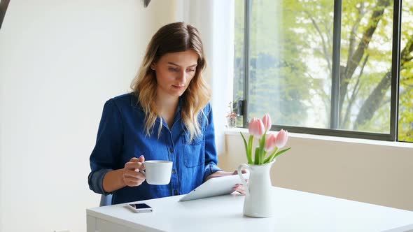 Woman using digital tablet while having coffee