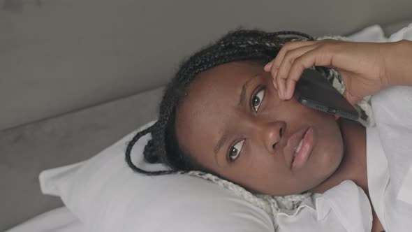 African American Woman Talking on Phone in Bed