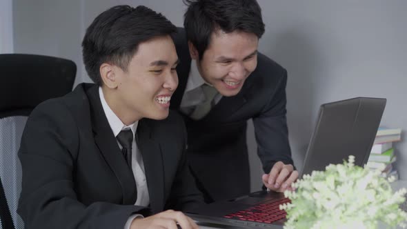 two business man laughing while using a laptop computer