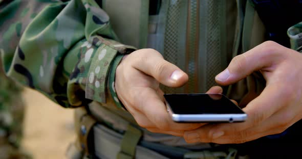 Mid section of caucasian military soldier using mobile phone during military training 4k