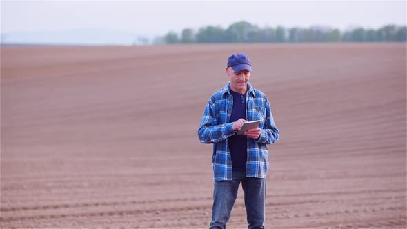 Farmer Examining Agricultural Field While Working on Digital Tablet Computer at Farm