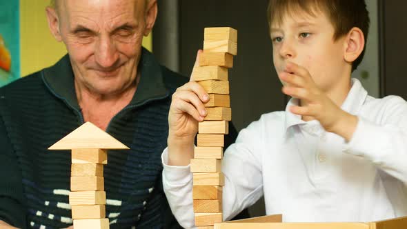 Caucasian boy 6-7 years old and grandfather 70 years old play board games. Active child with an elde