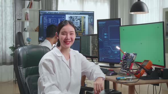 Development Facility:  Asian Woman Smiling To Camera. Female Working On Green Screen Computer