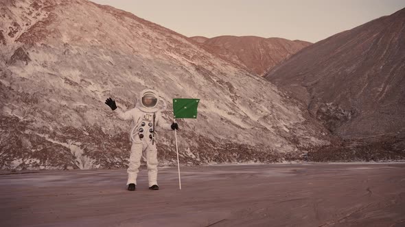 Astronaut on a Background of Hills with a Flag Waving Hand
