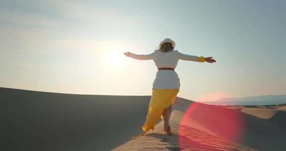 Young Woman Walking Barefoot in Desert at Sunset