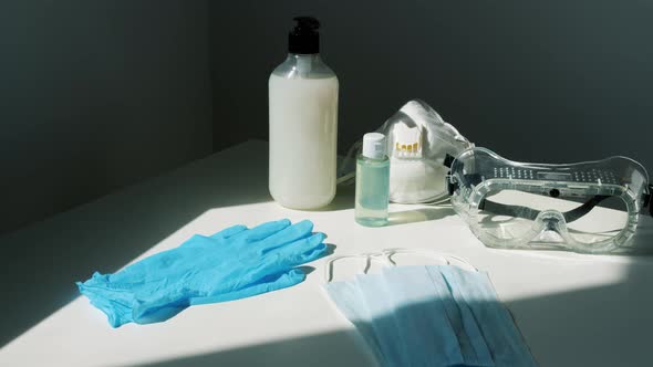 Concept Shot of Corona Virus Symbols - Sanitizers in Bottles, Medical Face Masks, Goggles and Gloves