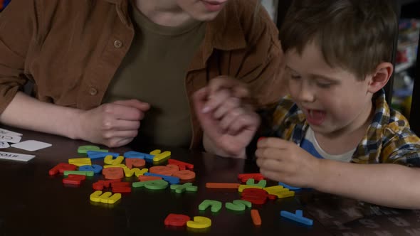 Mom teaches her son how to say the words on the cards at home at the table