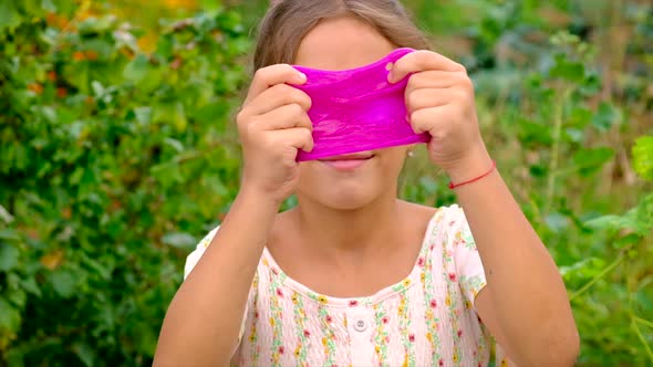 The Child Plays with a Slime in Her Hands