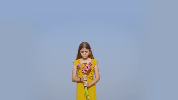 Girl Holds Flowers in Her Hand on the Background of Blue Sky