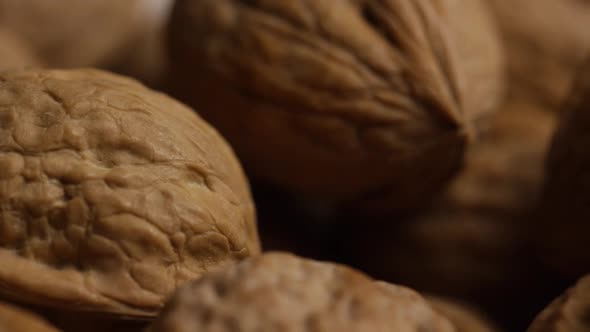 Cinematic, rotating shot of walnuts in their shells on a white surface - WALNUTS