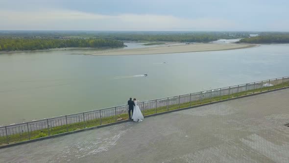 Newlywed Couple Looks at Calm River From Hill Bird Eye View