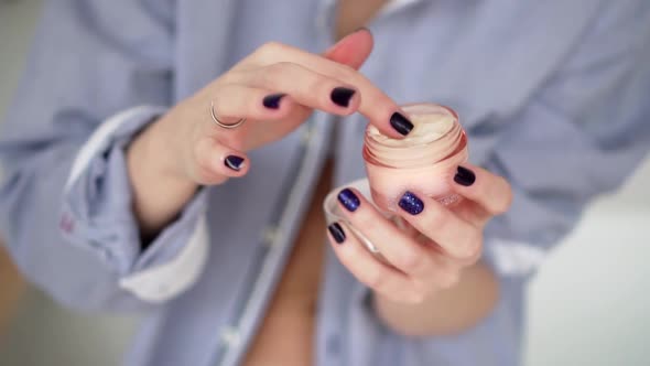 Woman hand taking a white moisturize cream from jar her finger. Skin care