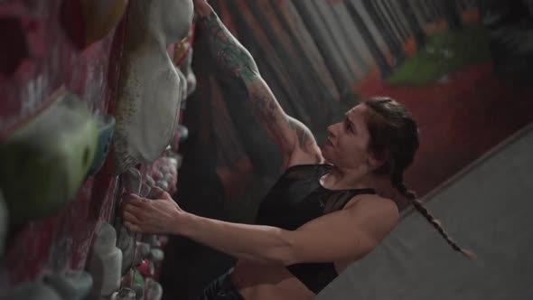 Athletic Woman Shows Effort and Focusing Climbing Artificial Rock Wall