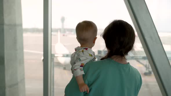 A Mother and Her Child Approach the Window at the Airport