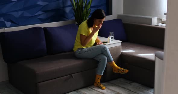 Woman sitting on sofa cough and drink water in the living room near cat