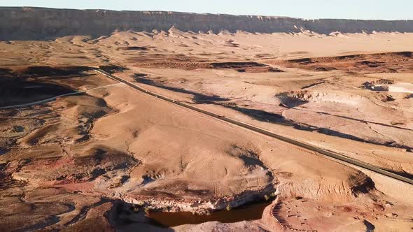 Aerial drone footage of cars on road. Retreat Shot of Cars passing by on desert highway road at sunn