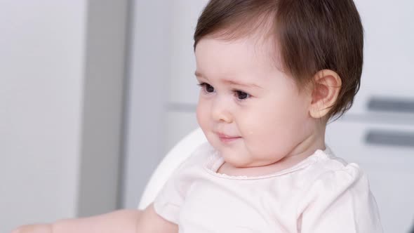 Baby Girl Eating Blend Mashed Food Sitting on High Chair Mother Feeding Child Hand with Spoon for