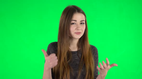 Portrait of Cute Brunette with Long Hair Is Showing Thumbs Up, Gesture Like on a Green Screen