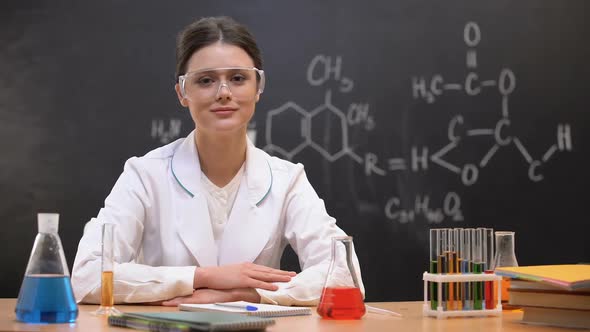 Female Scientist in Laboratory Looking to Camera, Equipment Standing on Table