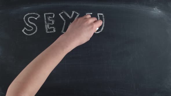 Term sexual education is written in large letters on a chalkboard and a condom is drawn, timelapse.