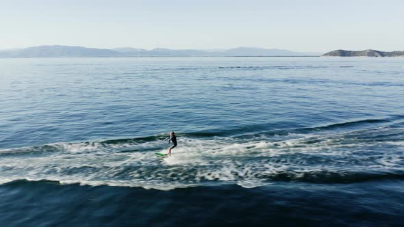 Drone view of kid doing water ski in the sea.