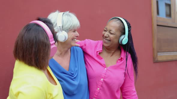 Multiracial Senior Woman Having Fun Dancing and Listening Playlist Music with Headphones Together