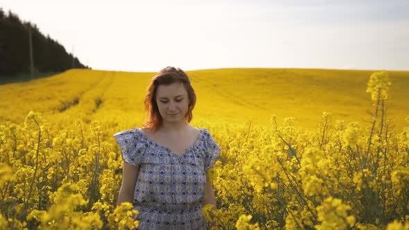 Young Romantic Woman Enjoys Spring in Rapeseed Field and Walks at Camera