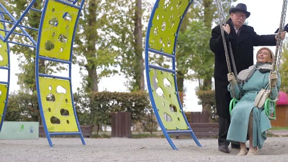 Senior couple on a playground, swinging on the swing set.