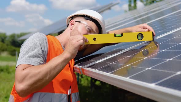 Worker Installing Solar Panels Uses a Level to Check That the Angle is Right