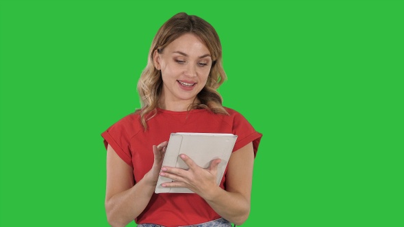 Blonde woman in red holding tablet and reading to camera